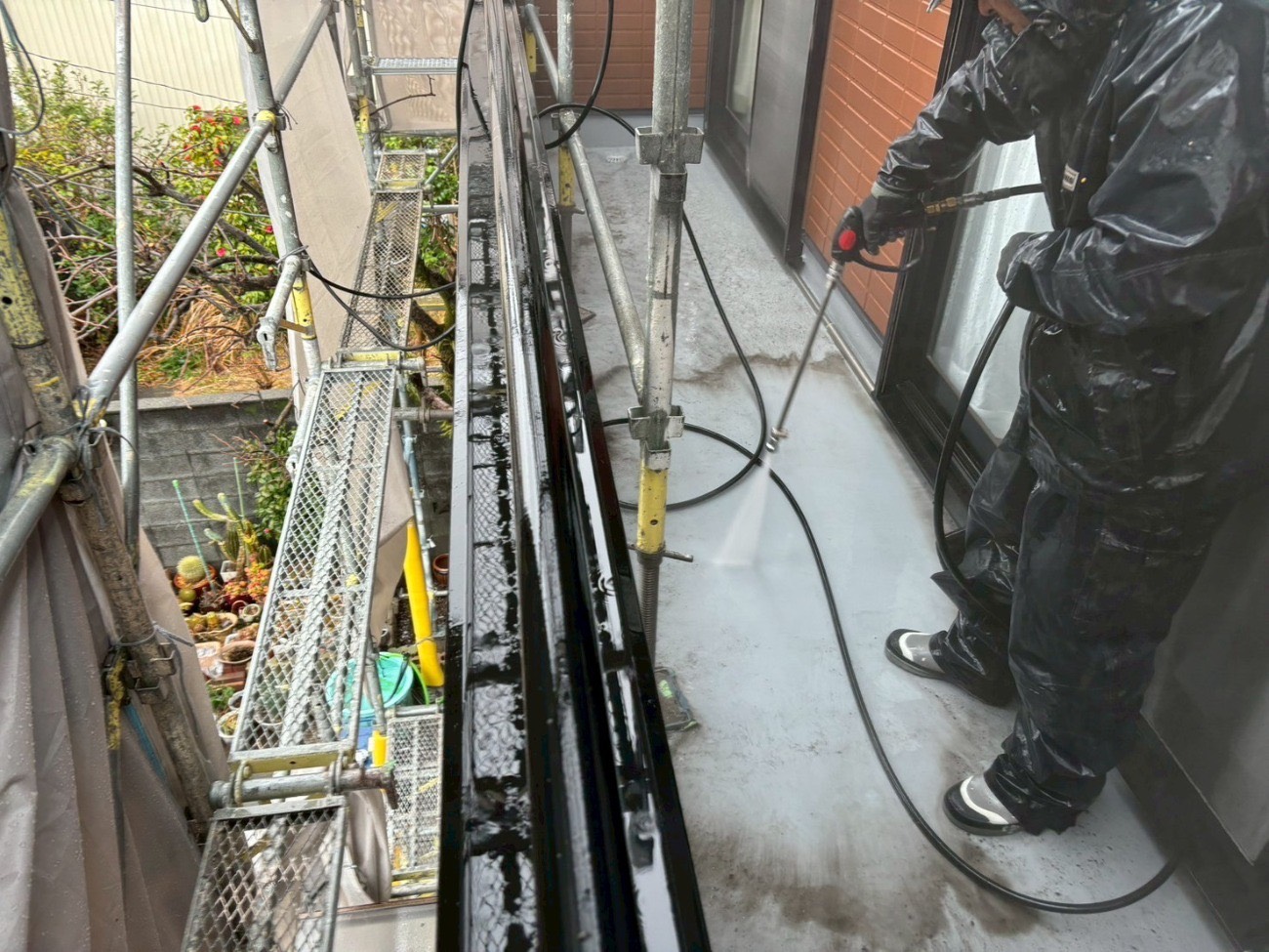 住宅のバルコニー床を高圧洗浄する様子