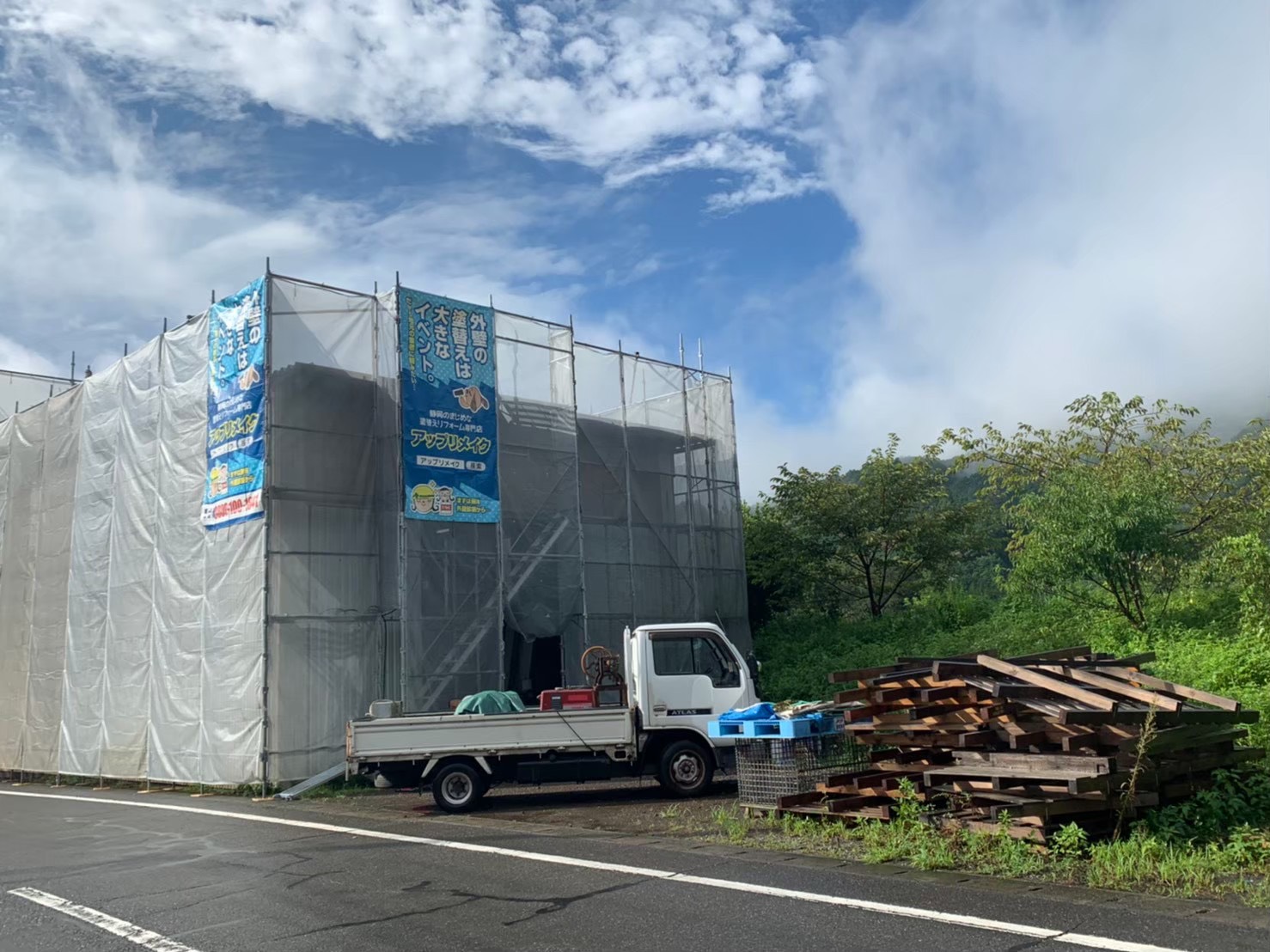 足場と養生シートを設置して屋根・外装工事を行う建物