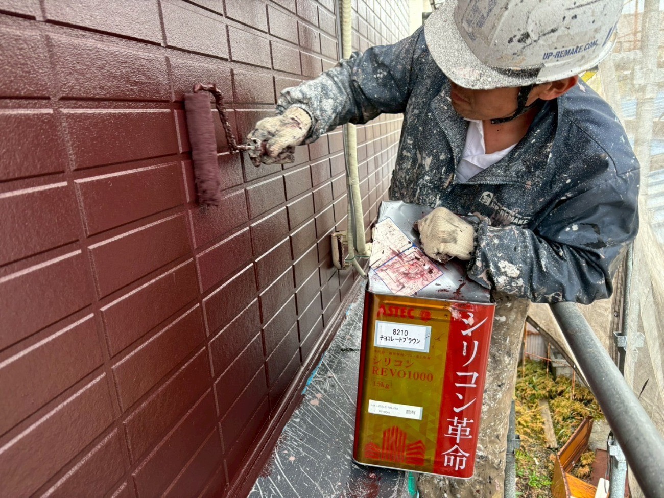サイディング外壁をローラーで上塗りする職人