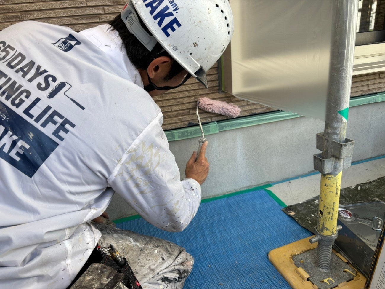 外壁下部に塗料をローラーで塗布している様子