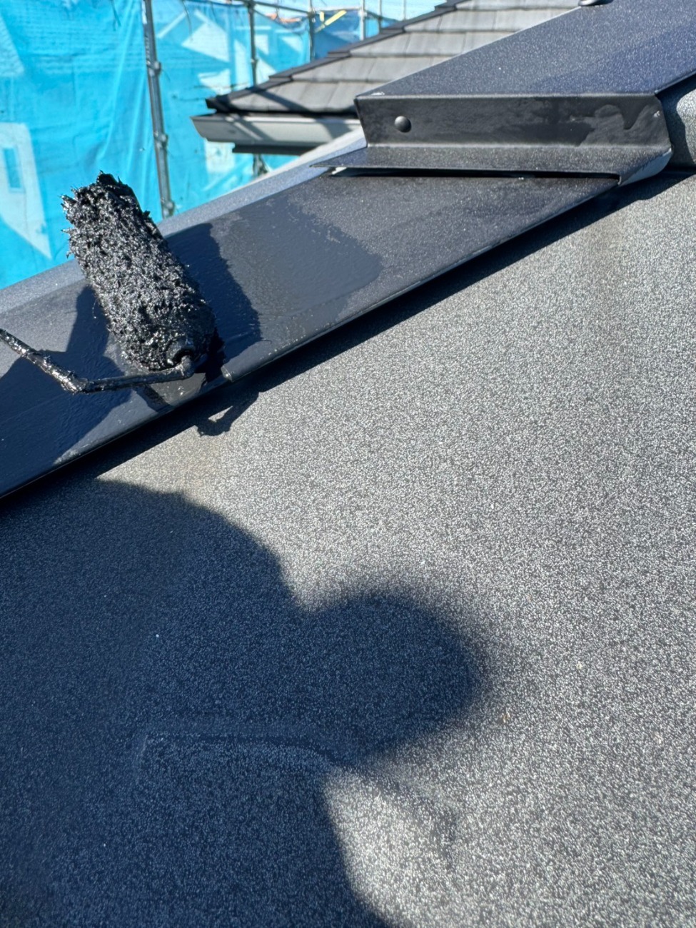屋根の金属板金部分に錆止め塗料を塗布している様子