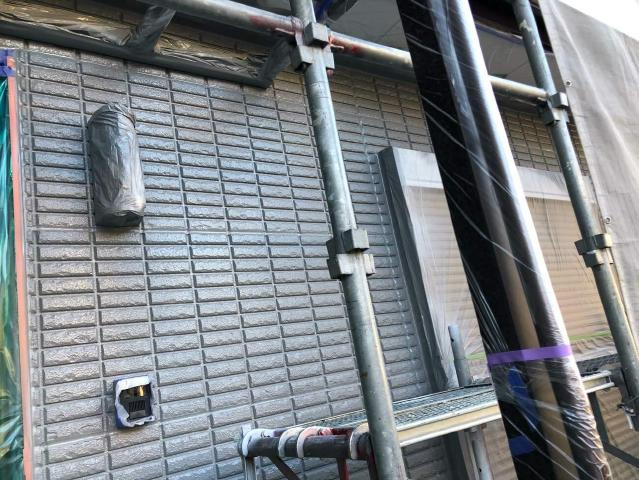 グレーを中心に塗装する、外壁の1回目の上塗り