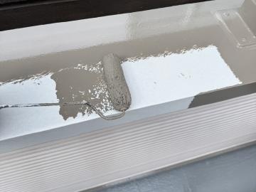 ベランダ笠木の1回目の上塗りです。白い錆止めの上から茶系で塗装します